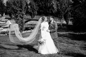 Black and white wedding portraits captured outdoors with flowing veil movement.
