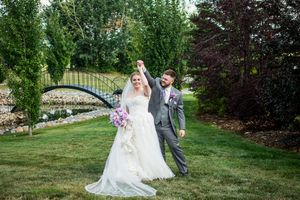 Wedding couple walking through lush garden landscape on stone pathway.