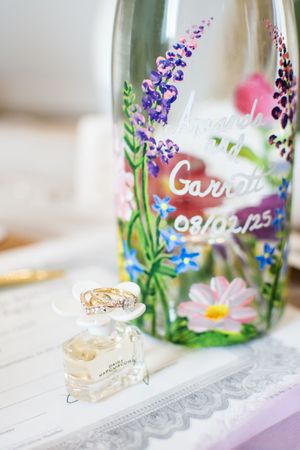 Hand-painted glass wedding decor with delicate floral designs and rings displayed on white lace.