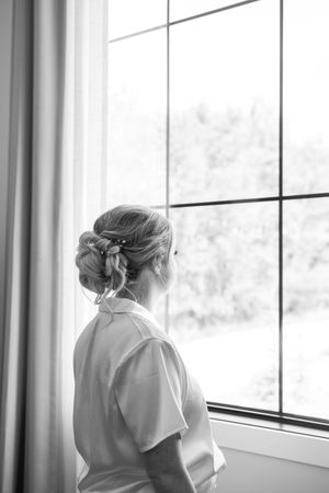 Black and white photo of three women looking out large windows in contemplative poses.