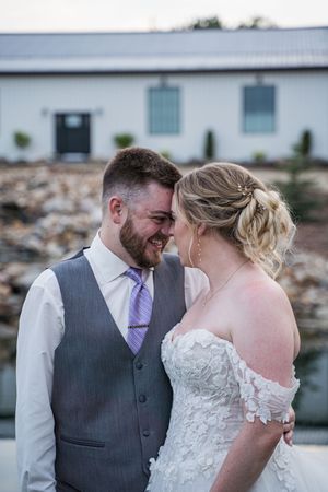 Intimate moment between couple against rustic barn backdrop.