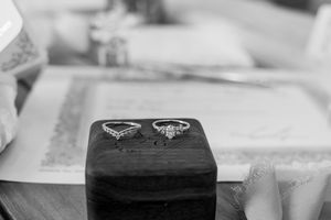 Two diamond engagement rings displayed on a black velvet box in black and white photography.