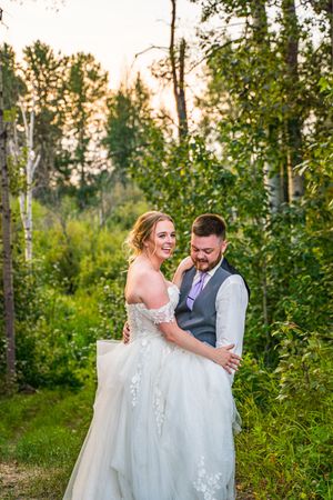 A couple shares a romantic moment together in a lush green orchard setting during golden hour.