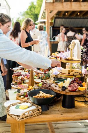 Elegant wedding reception grazing table with charcuterie boards and appetizers displayed on wooden stands.