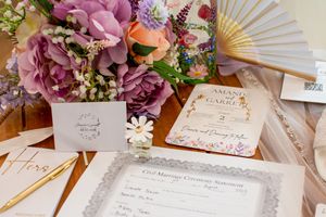 Wedding stationery and invitations arranged with pink flowers and a gold fan.