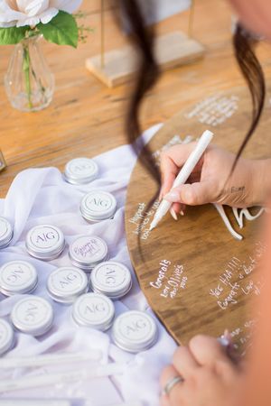 Wedding guest book signing station with purple monogrammed coasters on wooden table.