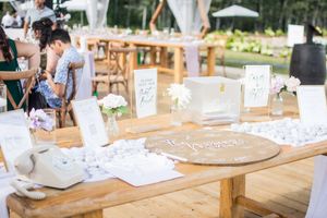 Wedding reception table setup with rustic wooden decor and white place settings.
