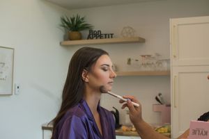 Getting ready room with makeup products and purple robes visible in a bright interior space.