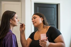Makeup application scene during wedding preparations.