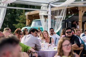 Outdoor wedding reception area with white draping and guests enjoying the celebration.