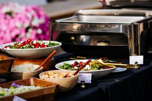Wedding reception buffet featuring colorful salads and appetizers in wooden serving bowls.