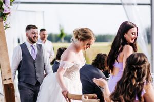 Wedding guests mingling and socializing during an outdoor reception under a white tent.