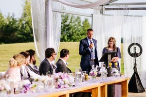 Elegant outdoor wedding reception setup with white drapes and floral centerpieces.