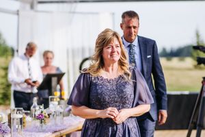 Wedding reception guests enjoying conversation at elegantly decorated tables with purple floral centerpieces.