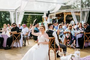 Panoramic view of wedding reception venue with white drapes and rustic wooden tables.