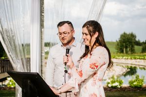 Wedding speech being delivered at outdoor venue with pond view in background.