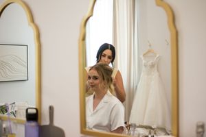 A bridal preparation scene showing a white wedding dress hanging in a mirror-lined dressing area.