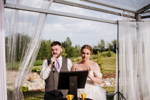 Wedding couple shares intimate moment in white draped gazebo during outdoor celebration.