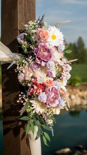 Beautiful wedding bouquet with purple roses, daisies and mixed flowers against wooden post.