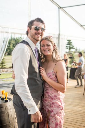 Wedding guests celebrate on an outdoor deck during a sunny afternoon reception.