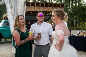 Outdoor wedding reception with guests mingling under string lights at dusk.