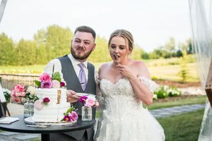 Wedding party enjoying cake and refreshments on an outdoor deck with white decor and floral arrangements.