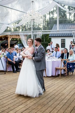 Wedding couple's first dance in a clear tent reception space.