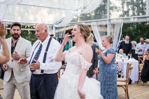 Wedding reception guests dancing and celebrating outdoors under string lights at dusk.