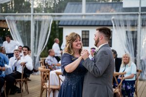 Wedding reception dance floor with guests celebrating under white tent and string lights.