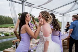Emotional moment shared between wedding attendees in purple and white dresses.