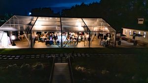 Illuminated outdoor wedding tent venue at night with string lights.