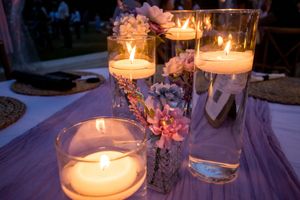 Close-up of romantic candlelit centerpieces with floating candles and pink floral arrangements.