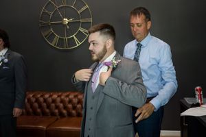 A sequence of images showing someone getting fitted for a gray suit jacket while standing in front of a vintage clock.