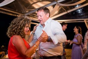 Couples dancing together at an evening wedding reception with dramatic lighting.