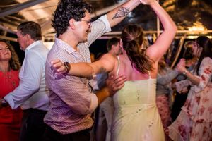 Wedding reception dance party with guests celebrating under warm lighting.