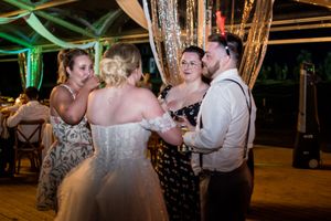 Evening wedding reception with guests dancing under colorful lighting and decorative elements.