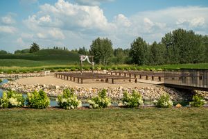 Panoramic view of an outdoor wedding venue with blue skies, green fields and decorative elements.
