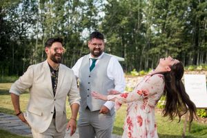 Wedding party posing playfully outdoors against a backdrop of trees and natural scenery.