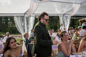 Outdoor wedding venue with clear tent and guests mingling during daytime celebration.