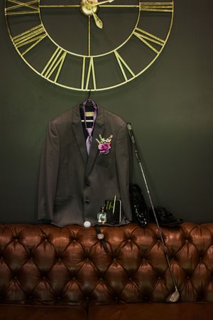 Dark suit jackets displayed against a wall with vintage clocks and leather seating.