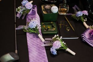 Purple and lilac floral arrangements laid out on dark surface with decorative elements.