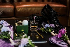 Wedding detail shots of purple floral arrangements and decorative elements in dark lighting.