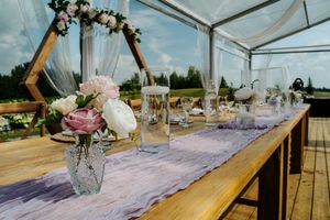 Wedding reception table with rustic decor, flowers in mason jars, and purple table runner.