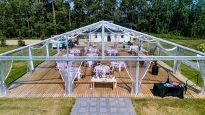 Clear tent reception setup with wooden tables and white decor overlooking a scenic landscape.