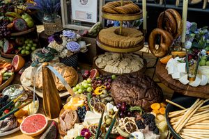 Lavish charcuterie spread with fruits, breads, and cheeses decorated with flowers.