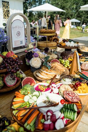 Elegant charcuterie board display with fresh fruits, vegetables, cheeses and meats arranged on wooden platters.