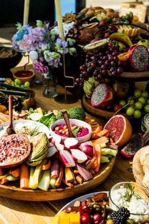 Elegant charcuterie board display with fresh fruits, meats, cheeses and colorful garnishes arranged on wooden platters.