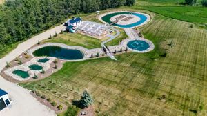 Aerial panoramic view of a large outdoor event venue with pools and landscaped grounds.