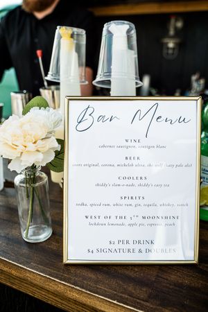 Elegant bar menu display at wedding reception showing drinks, wine and cocktail options.