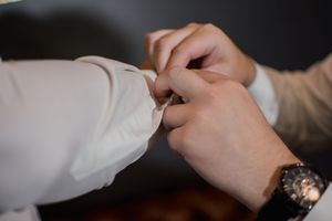 Close-up of hands adjusting formal attire during wedding preparations.